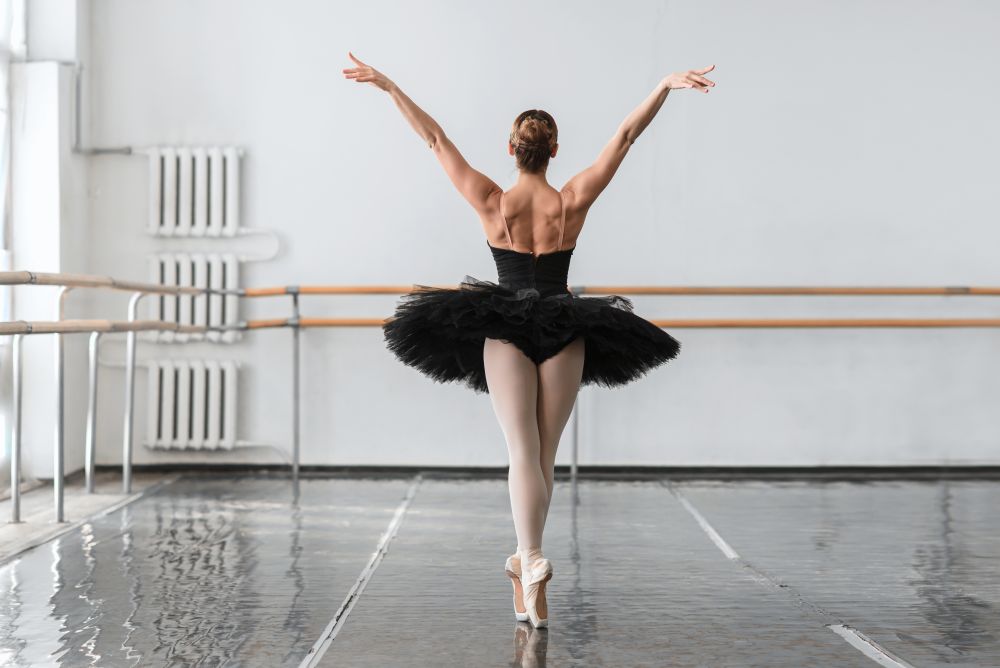 Graceful ballerina dance in ballet class, barrre and white wall on background