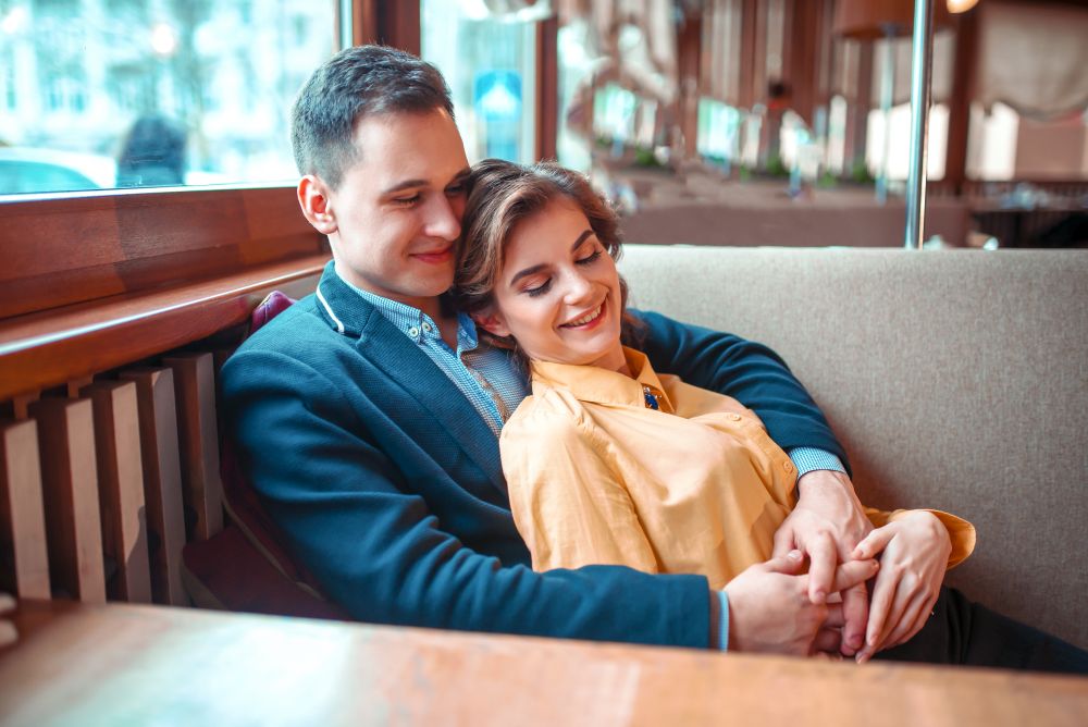 Cheerful love couple at romantic date. Happy man and woman hugs in restaurant.