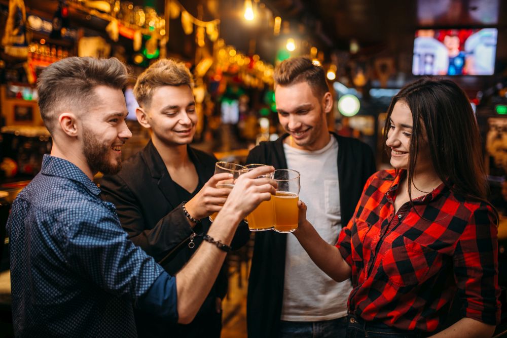 Happy football fans raised their glasses with beer at the bar counter in a sport pub, victory celebration. Happy football fans raised their glasses with beer