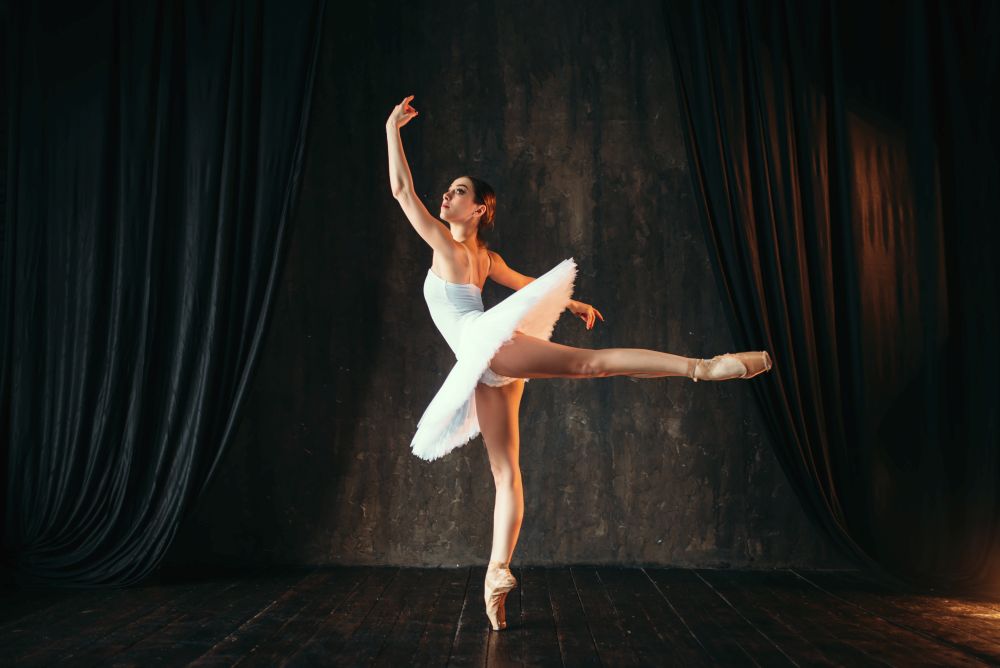 Graceful ballerina in white dress dancing in class. Ballet dancer training on the stage