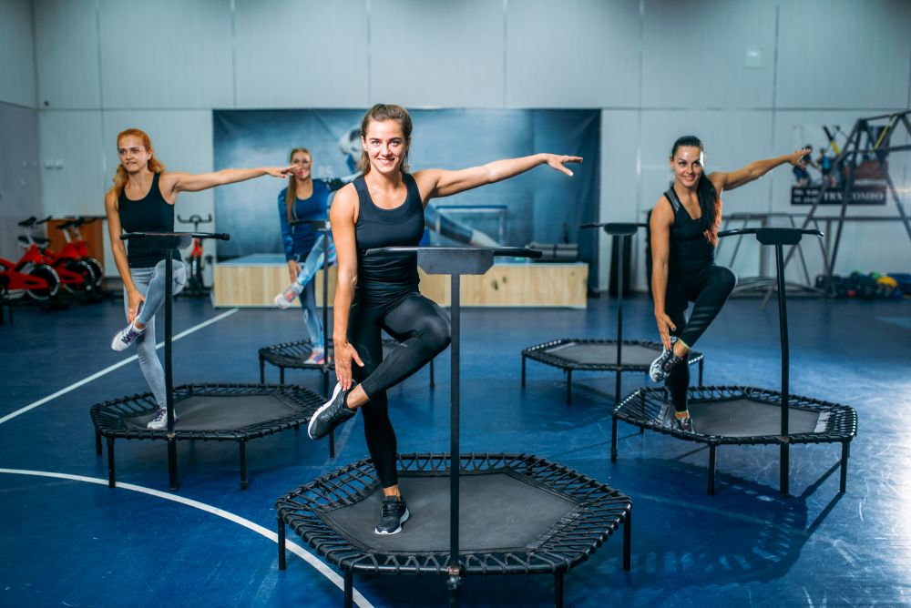 Women group doing fit exercise on sport trampoline, fitness workout. Female teamwork in gym. Aerobic class. Women group doing fit exercise on sport trampoline