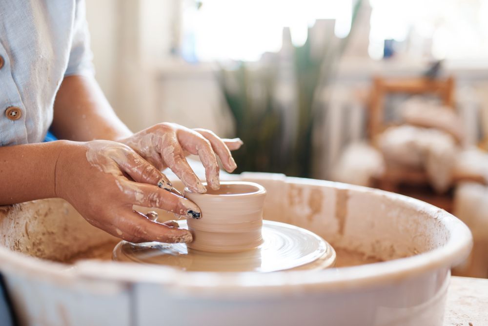 Female potter making a pot on pottery wheel. Woman molding a bowl. Handmade ceramic art, tableware from clay