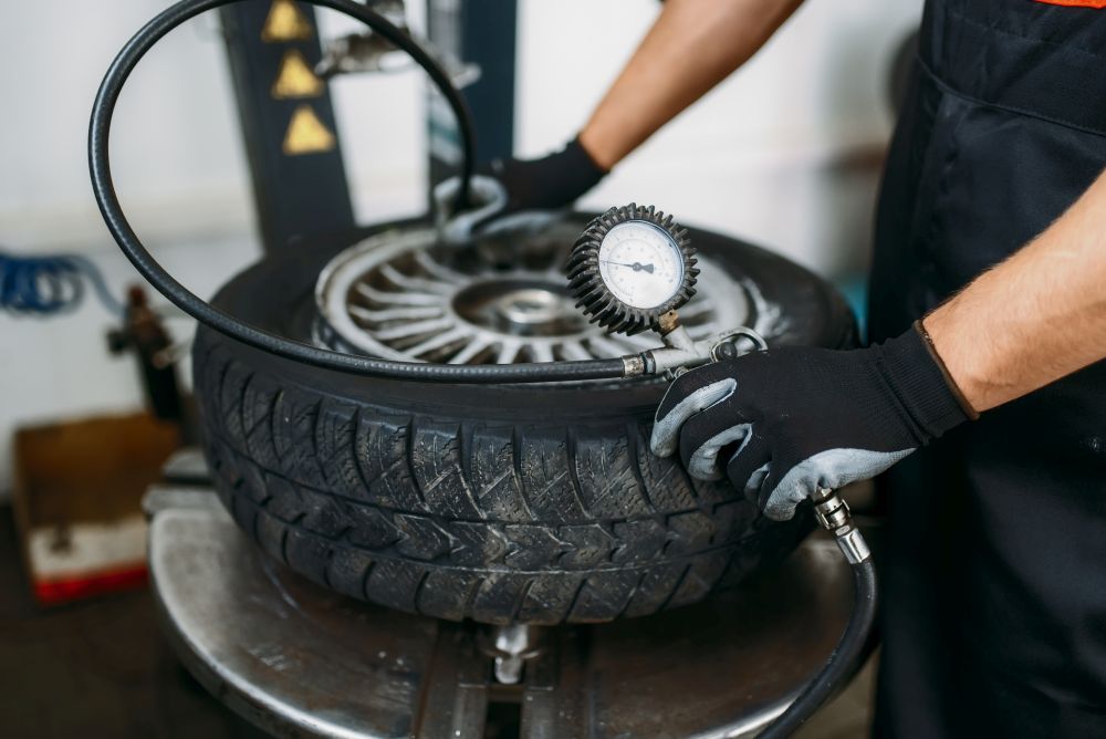 Mechanic inflates the wheel, tire repairing service. Man repairs car tyre in garage, professional automobile inspection in workshop