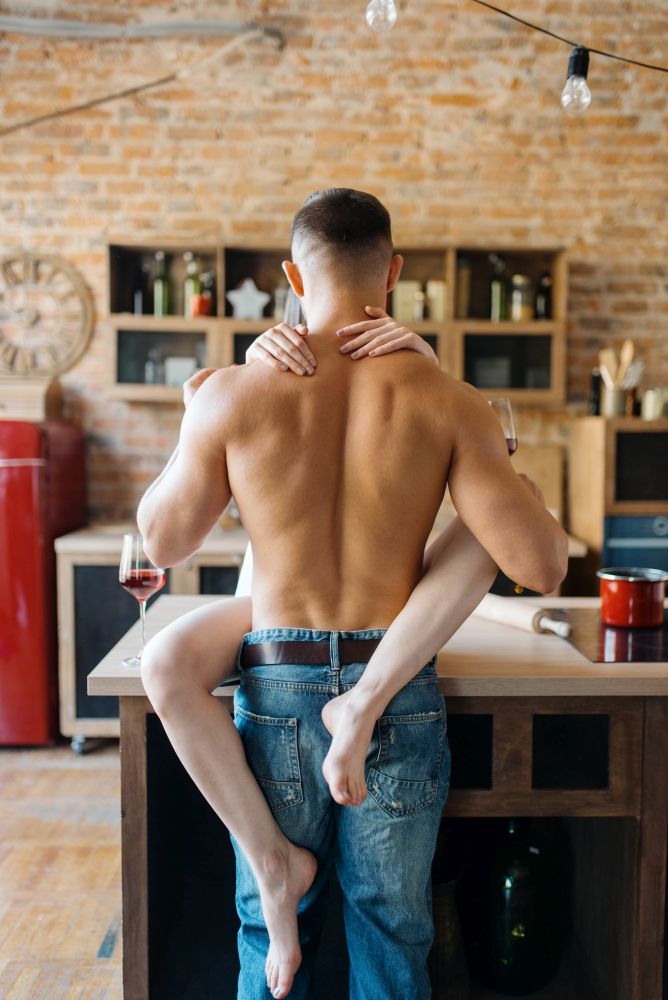 Sexy couple hugs on kitchen counter, romantic dinner. Man and woman preparing breakfast at home, food preparation with elements of eroticism