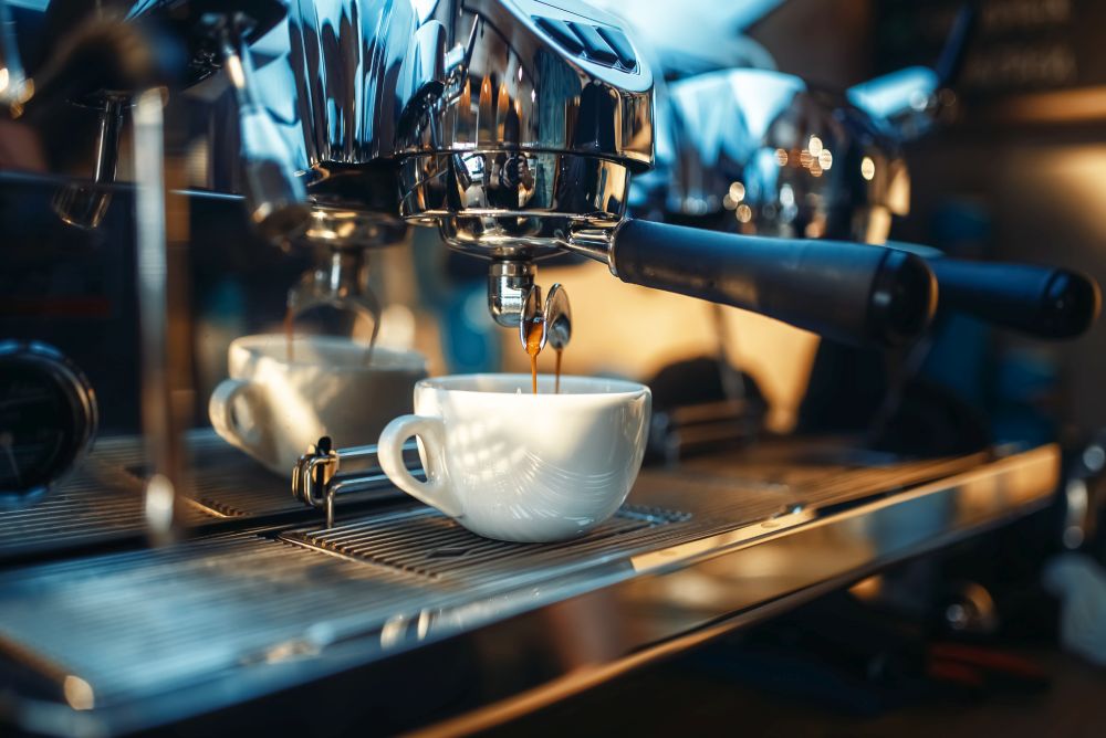 Espresso machine pours fresh black coffee into the cup closeup, nobody. Professional restaurant, cafe or cafeteria business equipment. Espresso machine pours fresh black coffee closeup