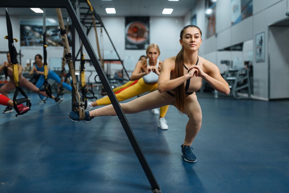 Women doing stretching exercise in gym. People on fitness workout in sport club, athletic girls in sportswear on training indoors. Women doing stretching exercise in gym