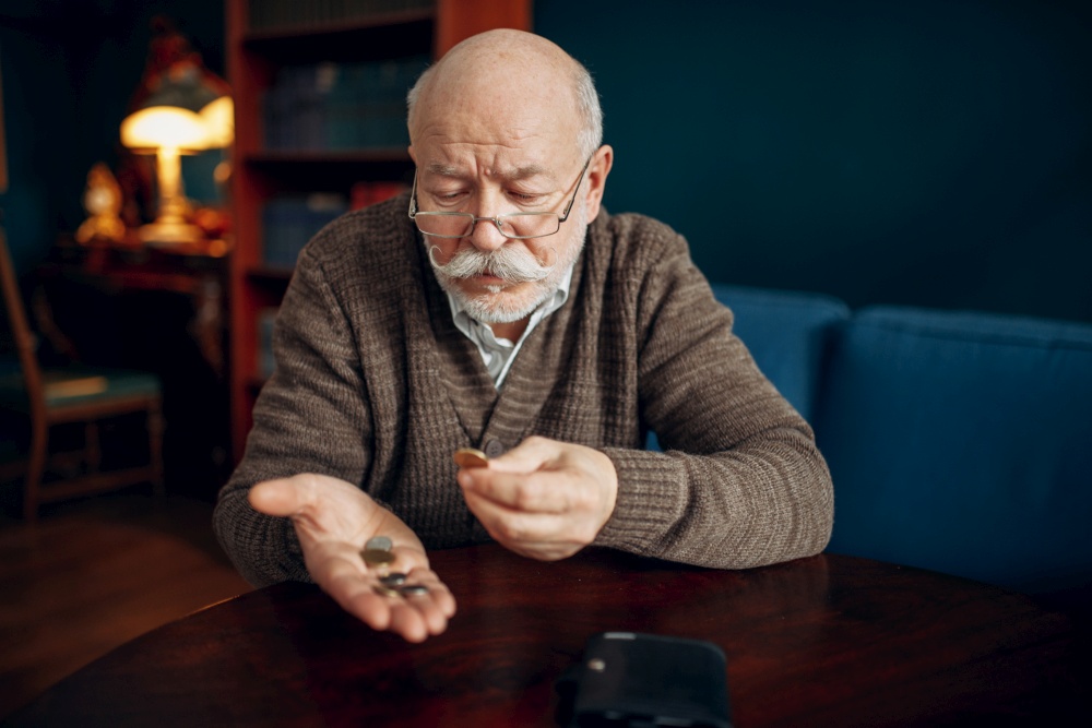 Pour elderly man holds some coins. Pour elderly man holds coins