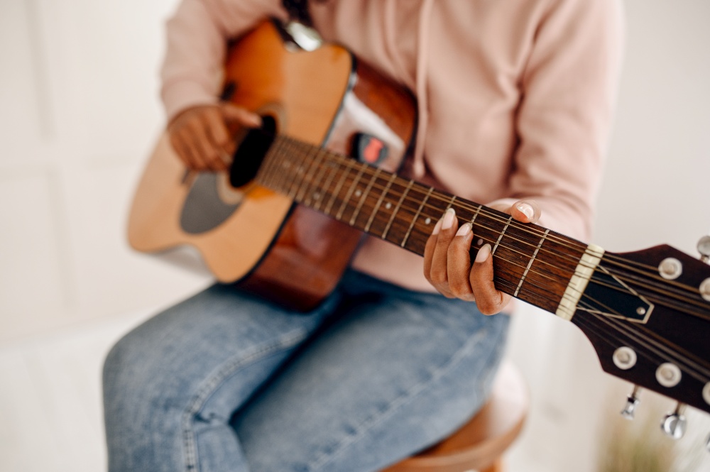 Woman play the guitar at home, closeup view. Pretty lady with musical instrument relax in the room, female music lover resting. Woman play the guitar at home, closeup view
