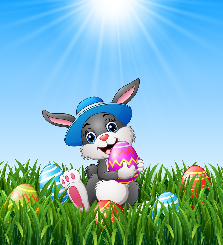 Happy easter bunny wearing a hat carrying easter eggs in the grass