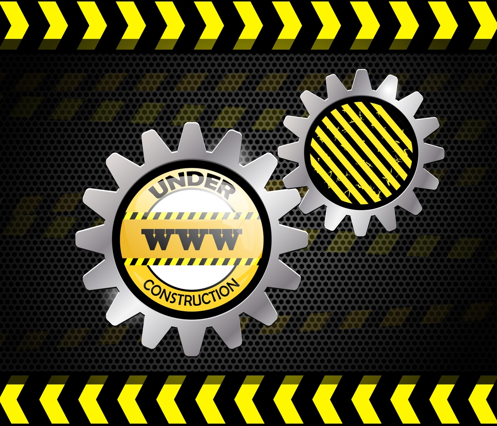 Under construction road sign in yellow on black with stripes and gears