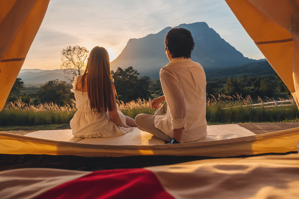 Asian couple enjoying outdoor camping Watching the sunset in nature
