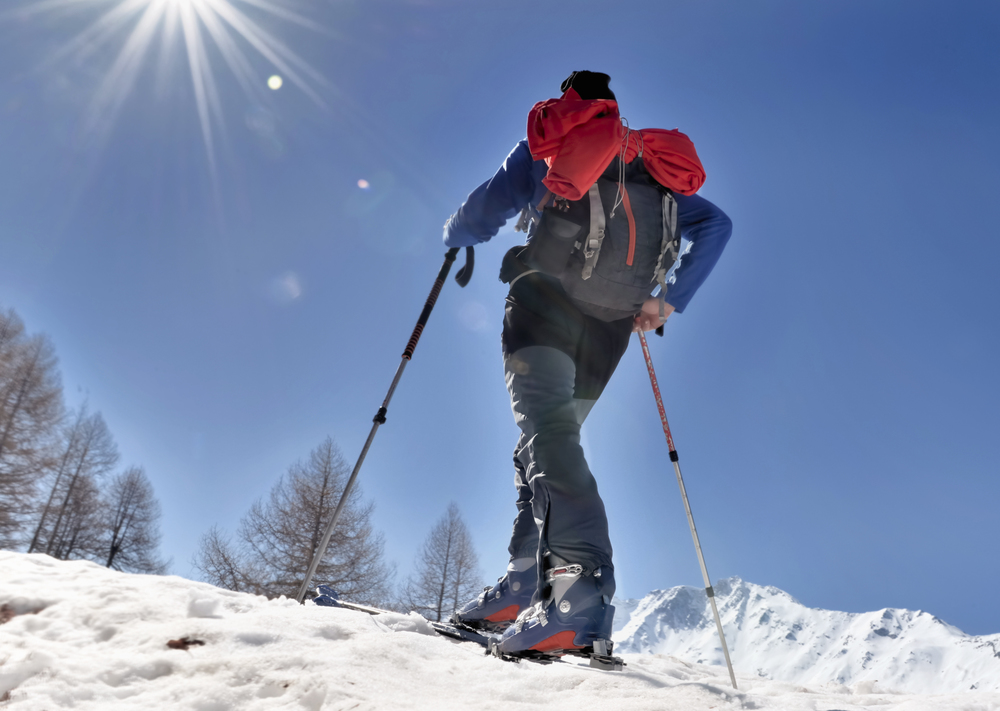 touring skier climbing mountain under sunny blue sky