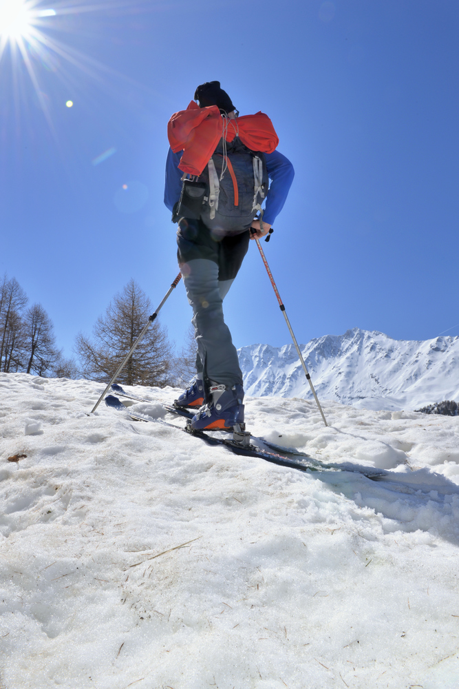 man hiking with ski touring in  snowy mountain under sunny sky