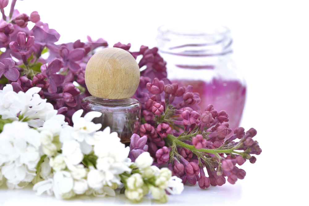 Glass flask among flowers of pink and white lilac on white background