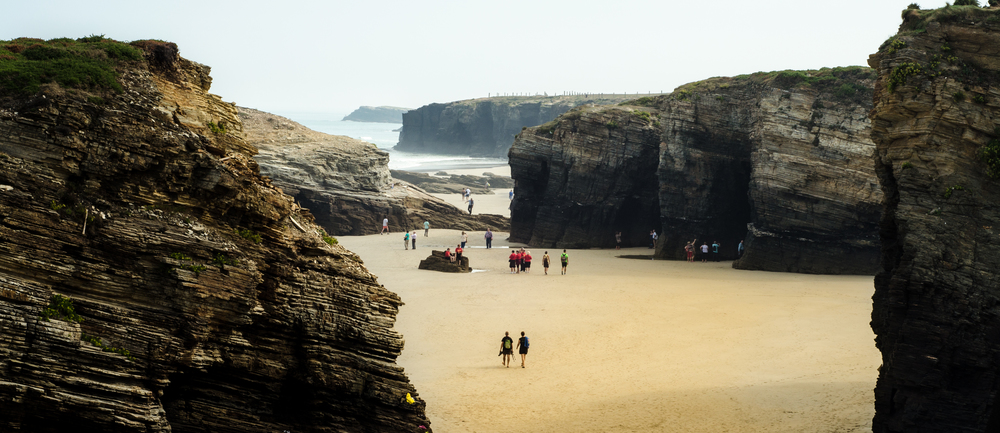 Cathedrals Beach&rsquo;s abrupt cliffs see people walking through them. Cathedrals Beach, Cantabria, Spain