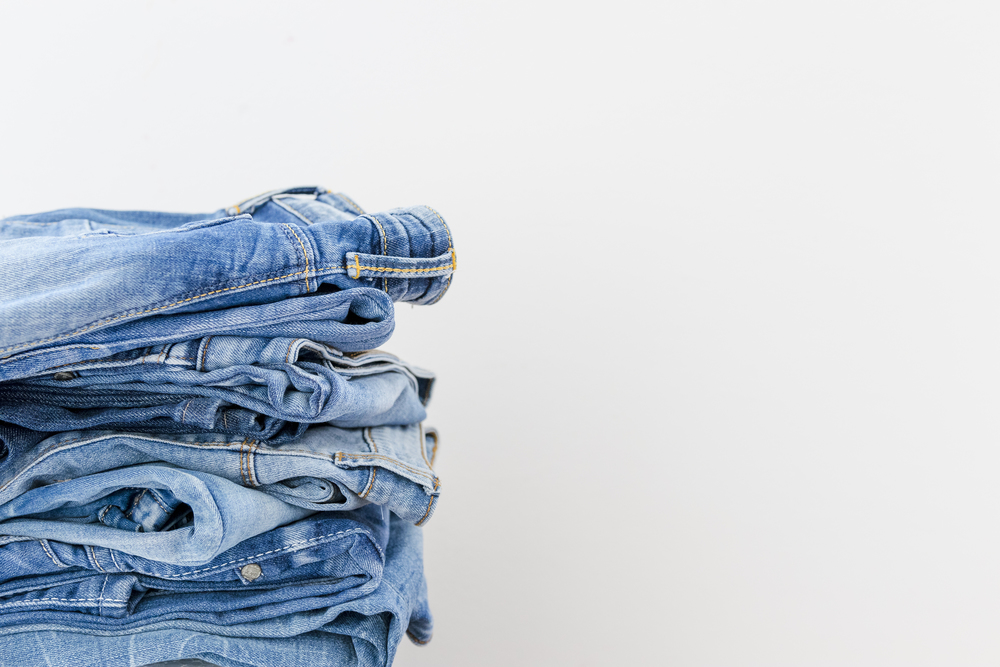 Stacked blue jeans on white background