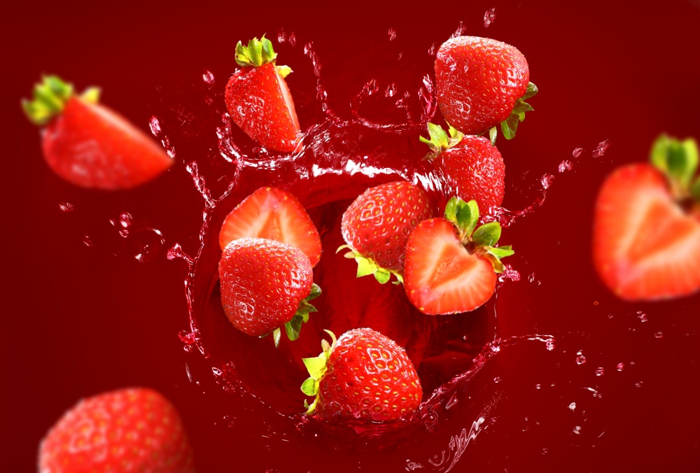 Strawberry falling into the juice with huge splashes