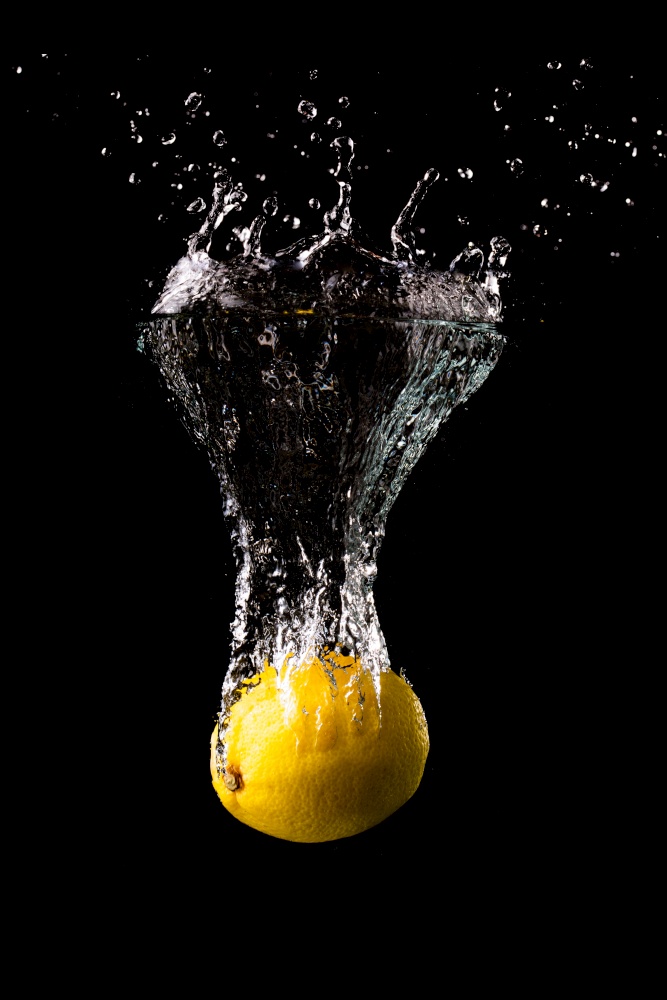 Fresh yellow lemon in water splash on black background with lots of air bubbles. Refreshment concept. Fresh yellow lemon in water splash on black background with lots of air bubbles.