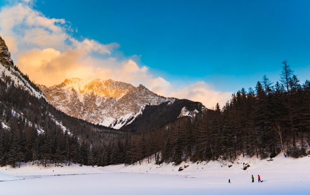 Peaceful mountain view at green lake. Frozen lake in winter during sunset with mountain peak in background. Famous tourist destination in Austria. Peaceful mountain view at green lake. Frozen lake in winter during sunset with mountain peak in background.
