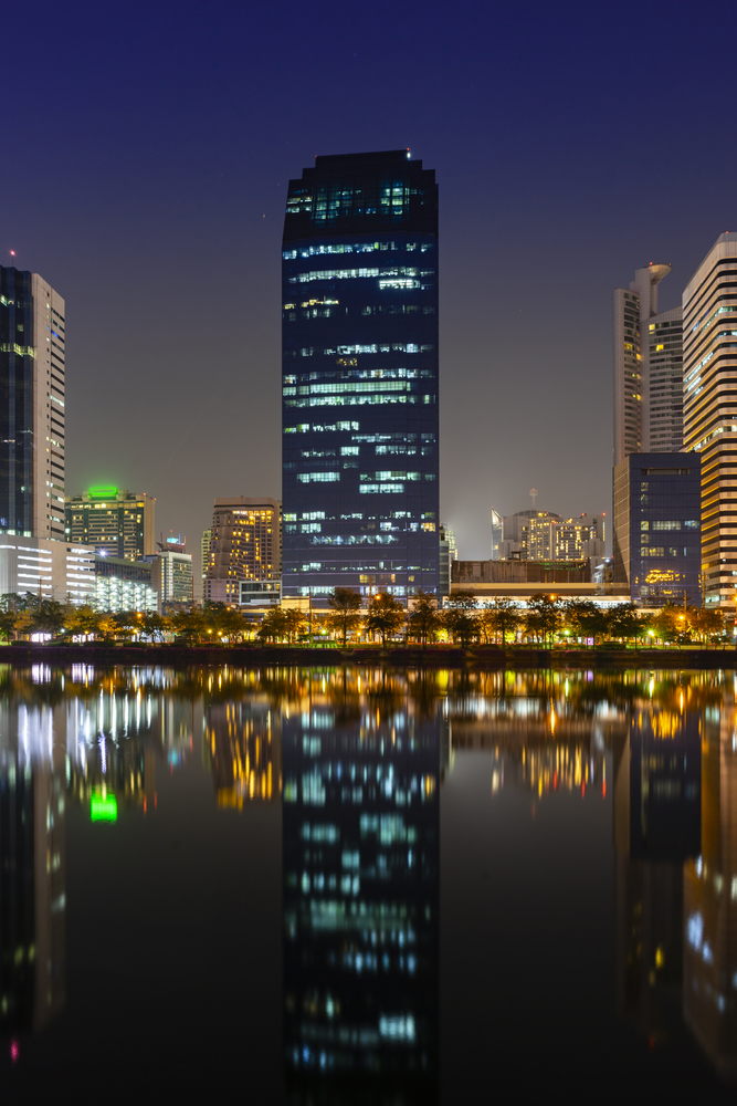 Building city in business area night scene with river reflection in Bangkok, Thailand.