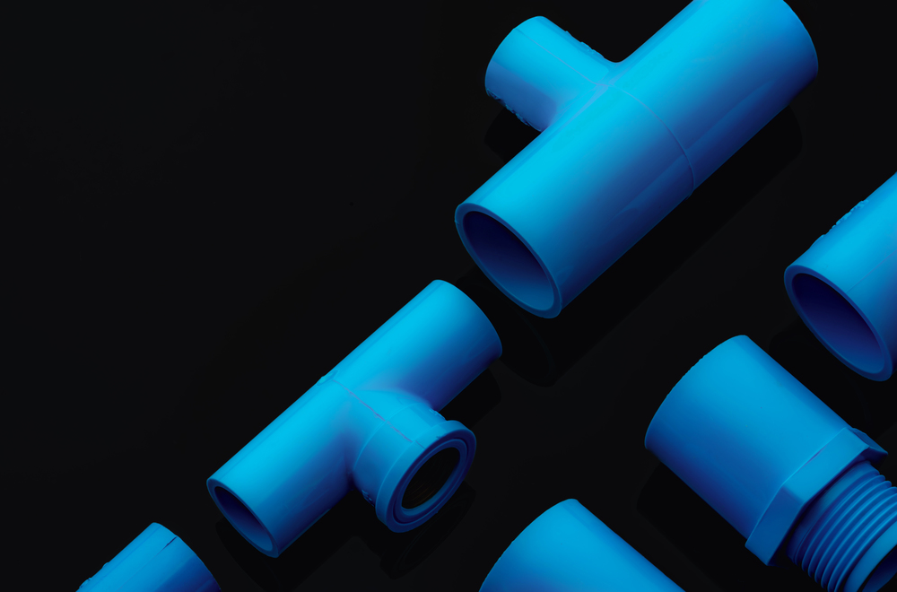 Set of blue PVC pipe fittings isolated on dark background. Blue plastic water pipe. PVC accessories for plumbing. Plumber equipment. Bend and three way connection plastic pipe for water drain sewage.