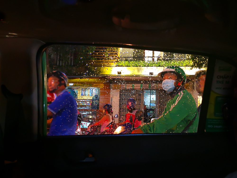 View through a taxi window in Saigon. A guy on a motorbike.