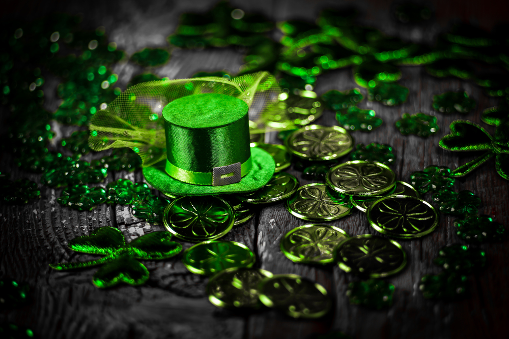 St. Patricks Day composition. Shamrocks, coins, leprechaun hat on vintage style wood background. St.Patrick&rsquo;s day holiday symbol. Close up view. Selective focus. Bokeh.
