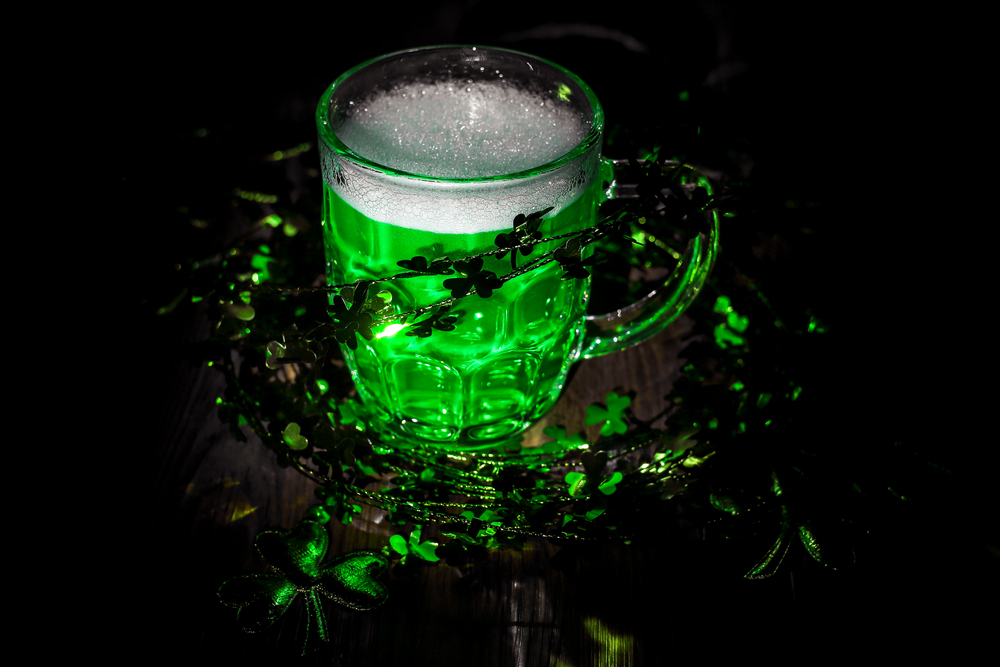 St. Patrick&rsquo;s Day. Green Beer pint on wooden table, decorated with shamrock leaves. Glass of Green beer close-up. Selective focus. Blurred background. Bokeh.