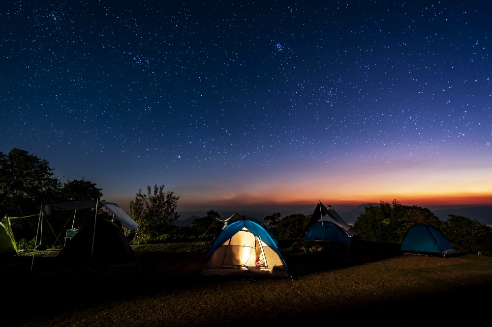 Glowing camping tent on the mountain under a beautiful starry sky at night, Travel lifestyle