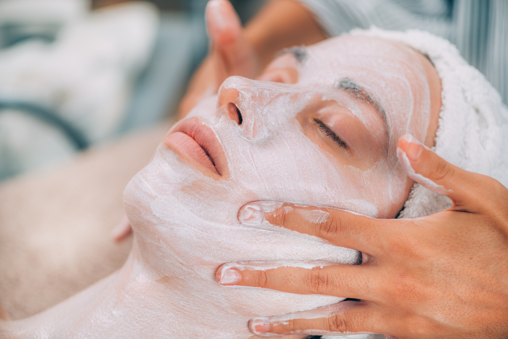 Cosmetologist applying rejuvenating facial mask onto woman&quot;s face in beauty salon. . Rejuvenating Facial Skin Mask Treatment