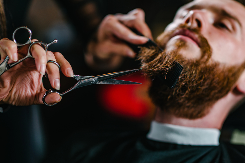 Barbershop, young man having a beard trimming