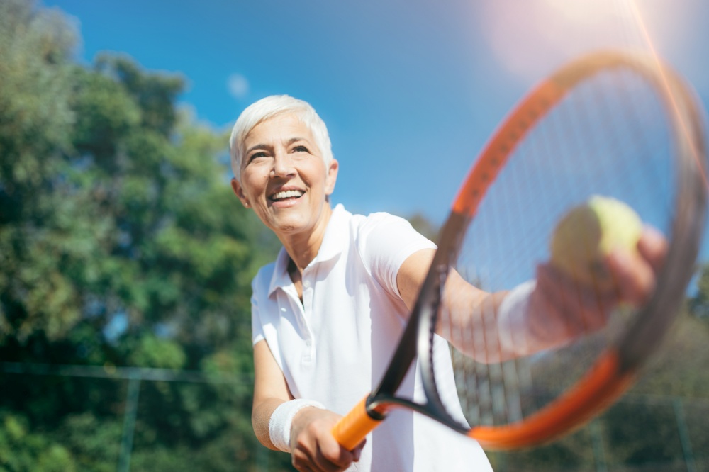 Senior Tennis - Pretty Mature Woman Serving Ball in Tennis