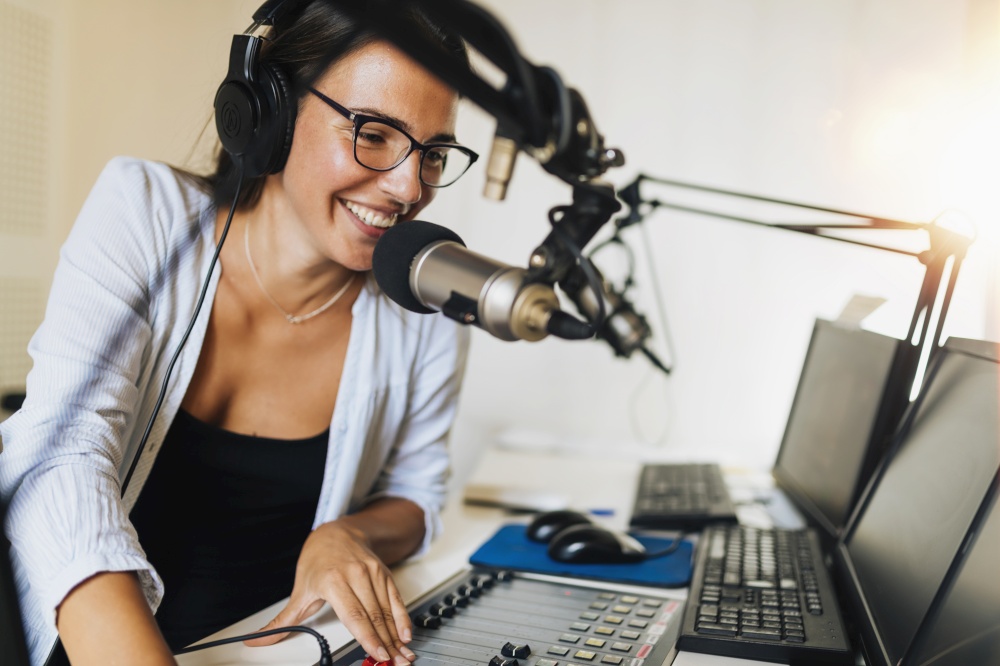 Attractive young woman wearing headphones and talking at online radio station talk show. Talk Show at Online Radio Station