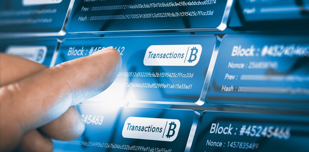 Finger pressing a blockchain block with the text transaction, a bitcoin symbol and security sha256 algorithm hach. Composite between a hand photography and a 3D background. Blockchain Technology. Bitcoin Transfer