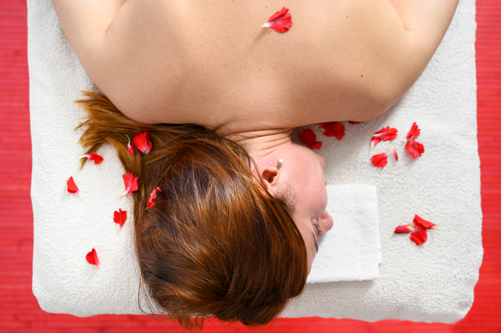 Relaxing woman in a spa with petal of flowers on her back, Beautiful woman relaxed in spa salon, body care, Spa body treatment .. Relaxing woman in a spa with petal of flowers on her back, Beautiful woman relaxed in spa salon, body care, Spa body treatment.
