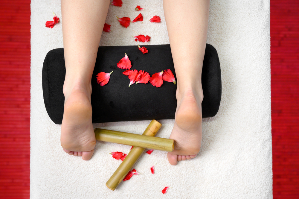 Female feet, bamboo sticks and flower petals. Thai massage, Spa and skin care concept . . Female feet, bamboo sticks and flower petals. Thai massage, Spa and skin care concept.