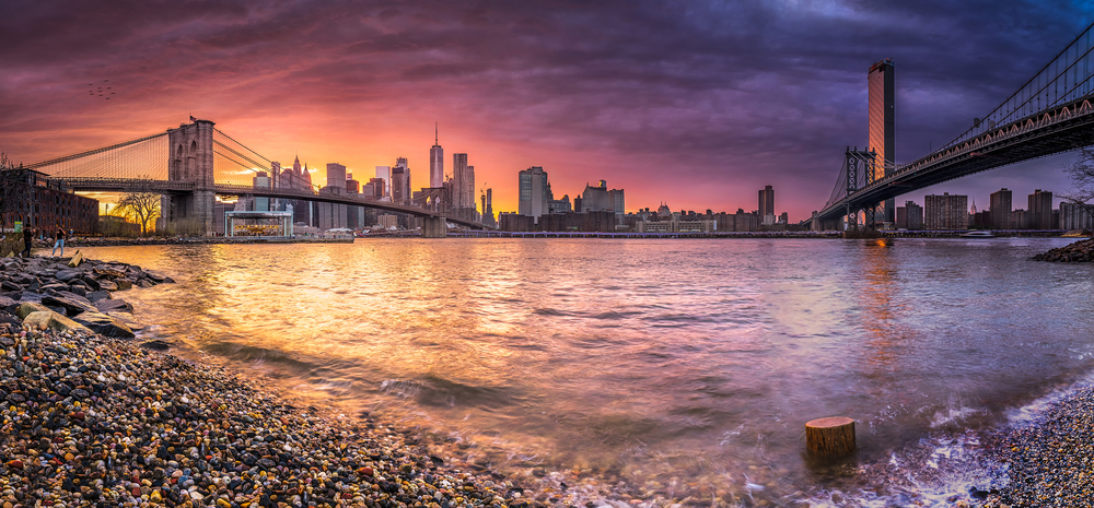 New york skyline reflection on the Hudson river at Brooklyn bridge and Manhattan Bridge at sunset on the shore