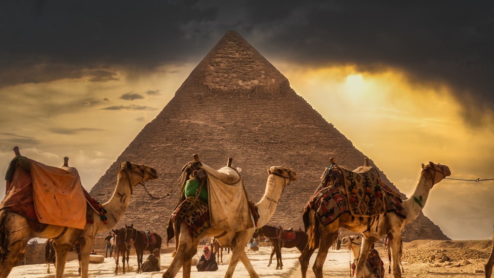 Giza, Egypt - January 29, 2020 - Tourist bustle with camels and people in front of a pyramid