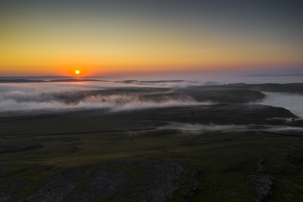 A drone shot capturing a misty morning over the Limestone crags of Malham
