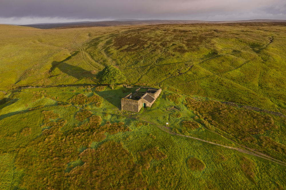 An aerial Sunrise drone shot of Top Withens or Top Withins, this farmhouse has been associated with "Wuthering Heights".