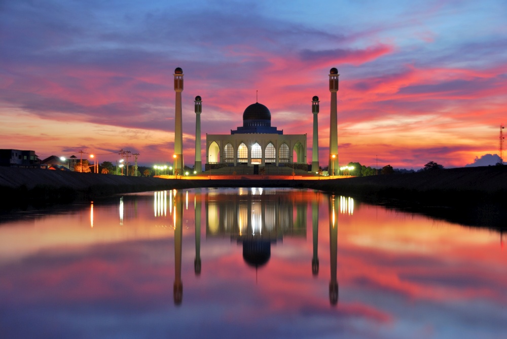 silhouette mosque on sunset time,silhouette with sunlight effect on sunset time and colorful sky background and water reflection