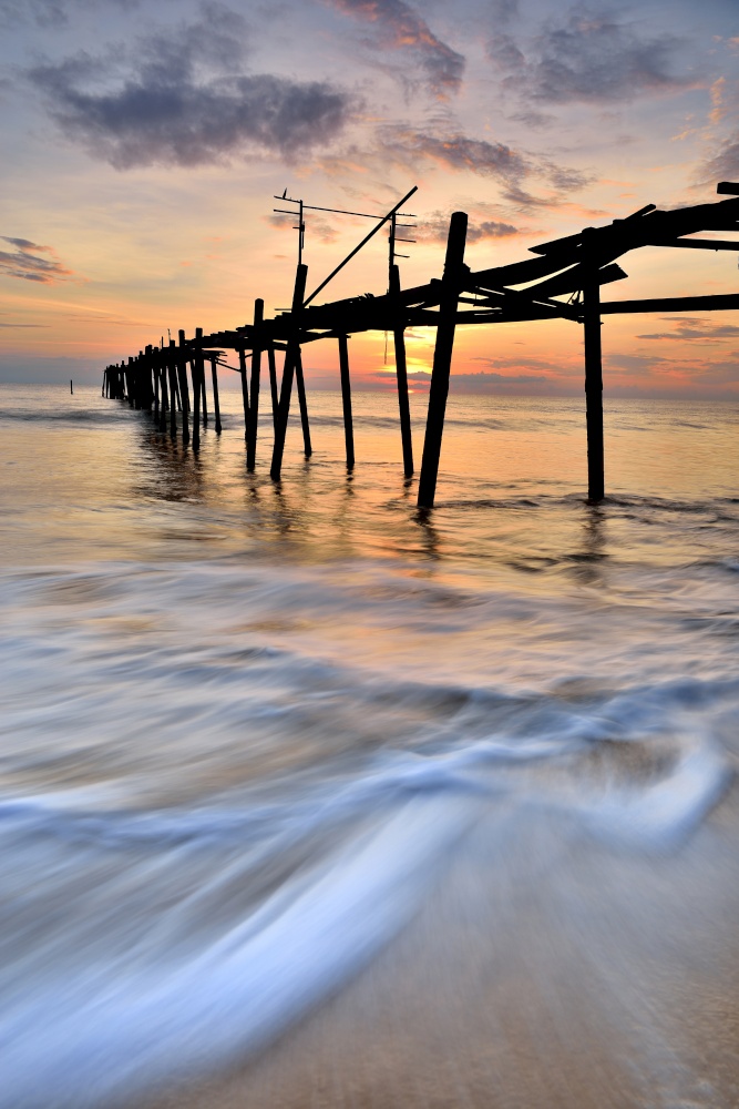 old wooden bridge in the sea with sunset