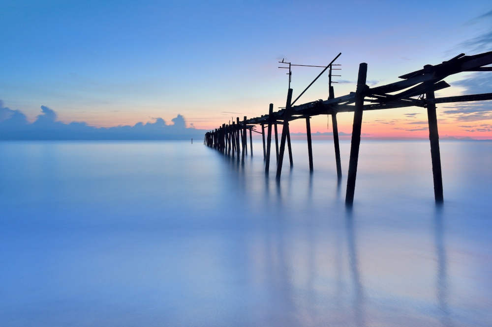 old wooden bridge in the sea with sunset