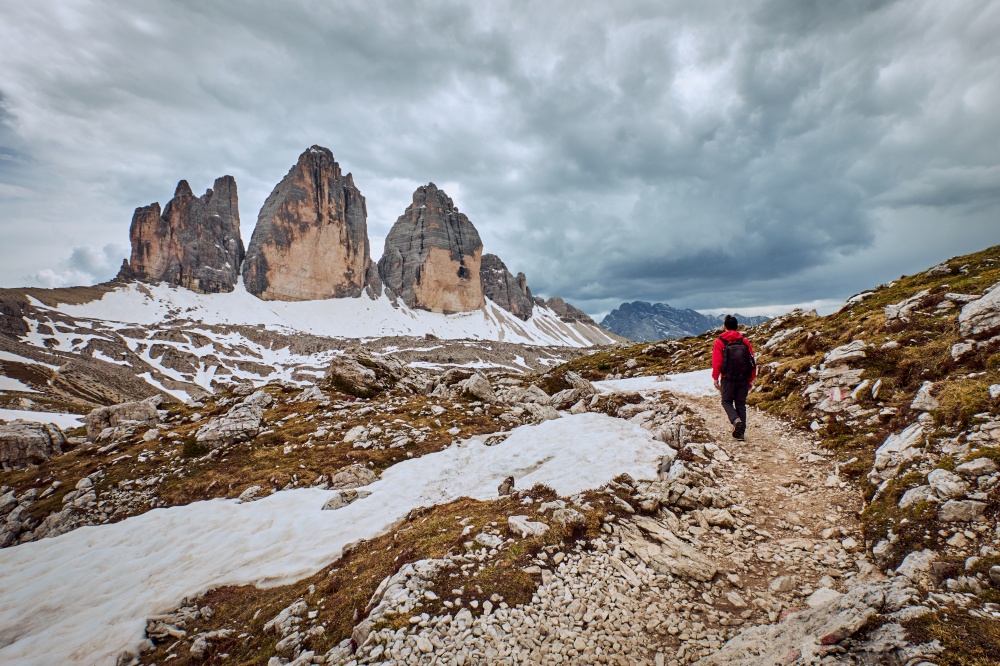 A hiker in a track with Tre Cime di Lavaredo in the background, located in Dolomites, Italy
