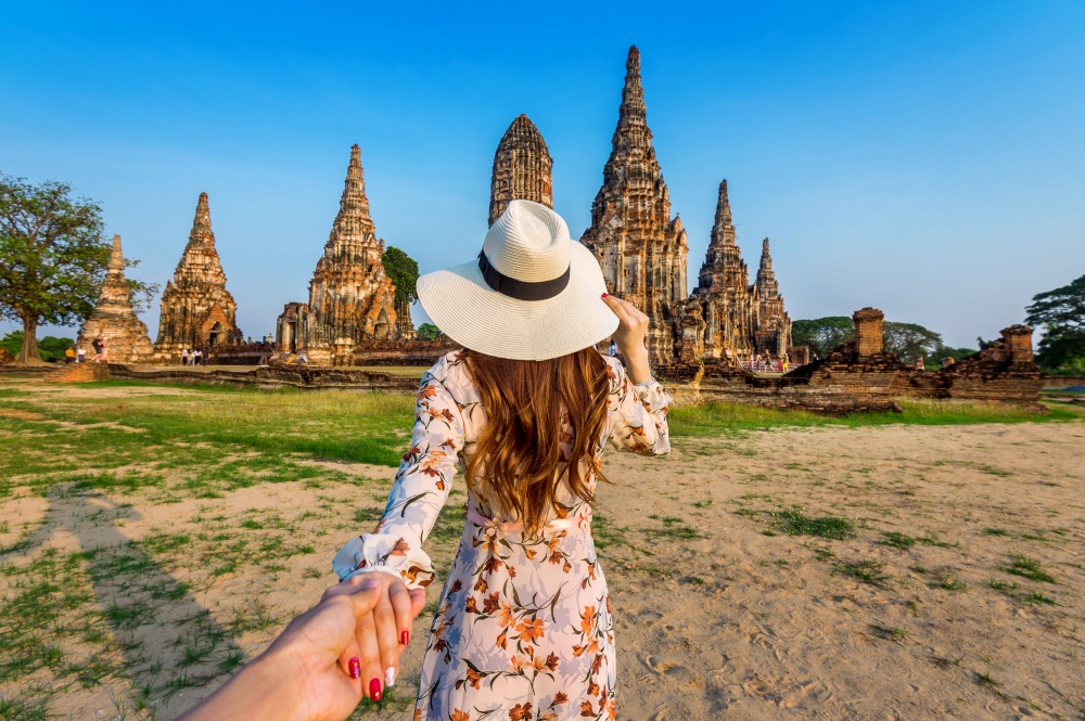 Woman holding man&rsquo;s hand and leading him to Ayutthaya Historical Park, Wat Chaiwatthanaram Buddhist temple in Thailand.