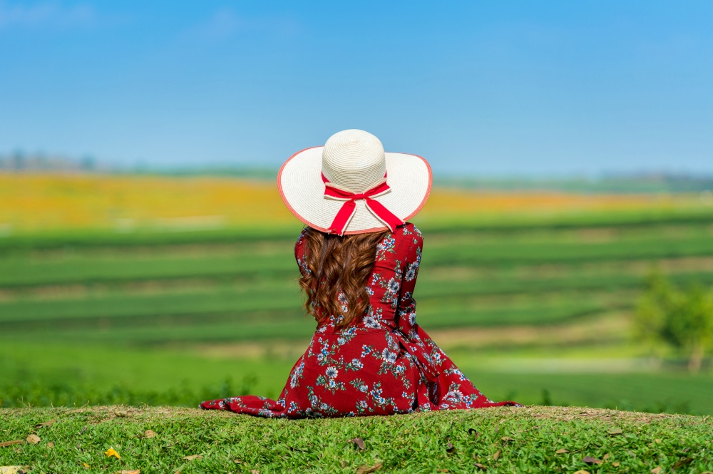 Woman sitting on green grass in green tea field.