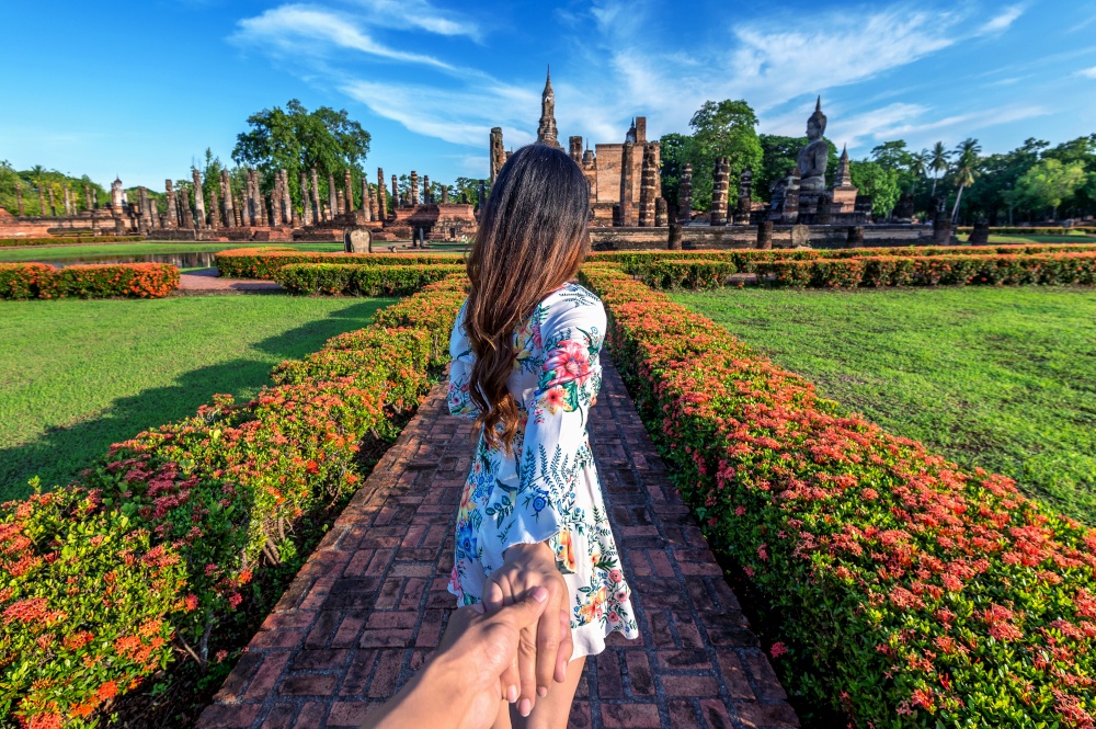 Woman holding man&rsquo;s hand and leading him to Wat Mahathat Temple in the precinct of Sukhothai Historical Park, Wat Mahathat Temple is UNESCO World Heritage Site, Thailand.