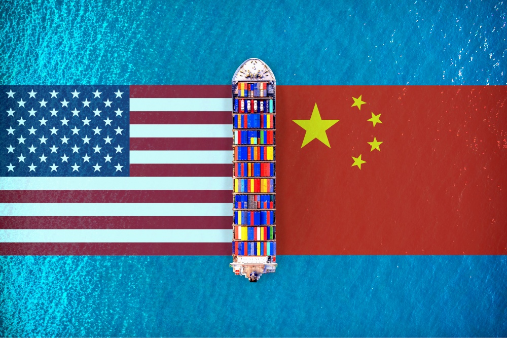 America flags and chinese flags with Cargo ship on ocean. USA and China trade war.