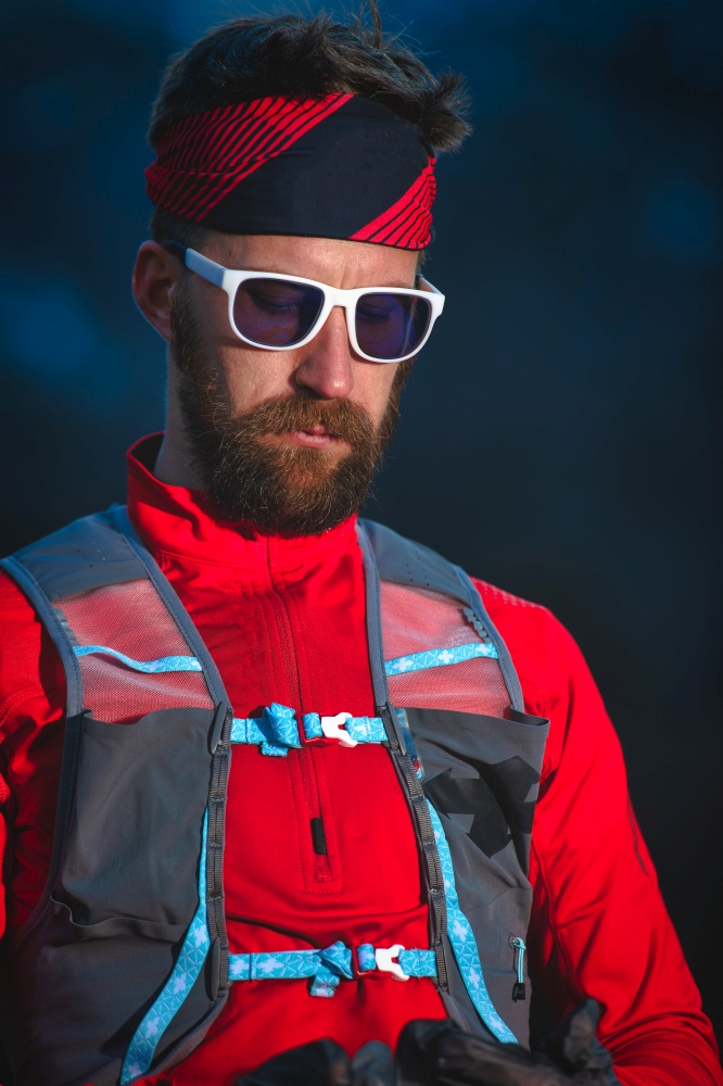 Young man with sporty beard with glasses and long distance running equipment
