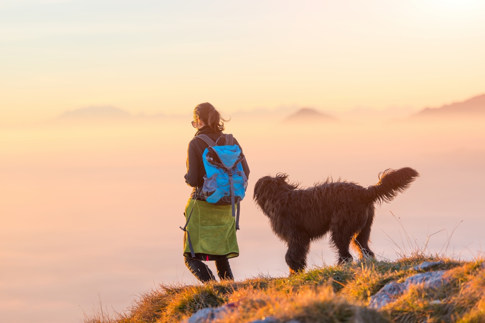 Woman with her black shepherd walking on a mountain above the Sea of Fog